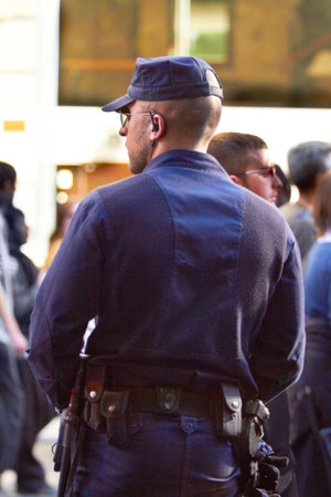 Hes on crowd control. Rearview shot of a policeman doing crowd control.の写真素材