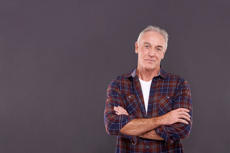 Content with life. Studio portrait of a confident elderly man against a gray background.の写真素材
