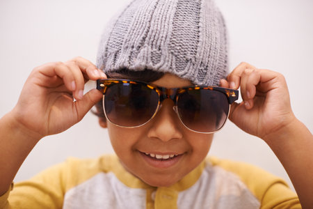 This kids got style. Portrait of a cute little boy wearing sunglasses and a beanie.の写真素材