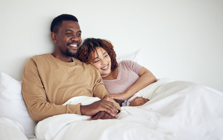 Black couple, bedroom tv watching and bed rest in the morning together with love and care. Happiness, home and smile of a woman and man feeling happy about streaming a movie in a house with bondingの写真素材