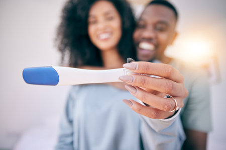 Pregnancy test, happiness and black couple in a home with a smile from baby news. Support, care and blurred background of a young and new mother and dad together feeling love with pregnant womanの写真素材