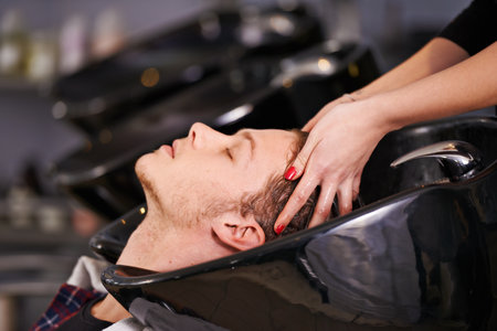 Wash away the stress. a young man having his hair washed at a hair salon.の写真素材