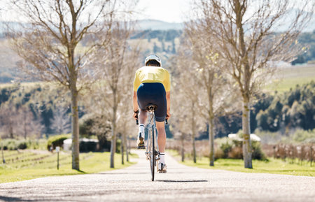 Back, man and bicycle for fitness, training and workout for wellness, healthy lifestyle and fresh air. Male athlete, biker and guy on road, cycling and practice for competition, exercise and hobbyの写真素材