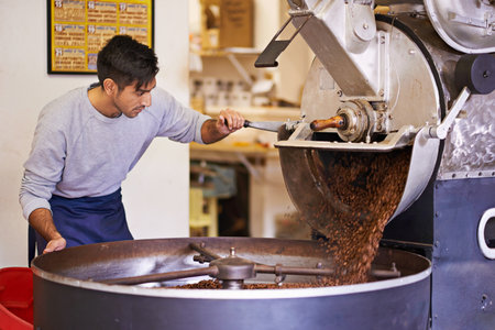 Beginning the journey to your cup. a machine grinding and roasting coffee beans.の写真素材