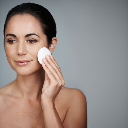 Cleansing her face with care. an attractive mid adult woman holding a cotton pad to her face.の写真素材