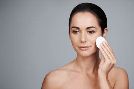 Fresh-faced and beautiful. an attractive mid adult woman holding a cotton pad to her face.の写真素材