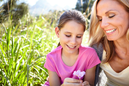 A flower for the best mom. a young girl and her mother picking flowers.の写真素材