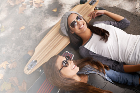 Chilling out at the skate park. two young women with their skateboards in the city.の写真素材