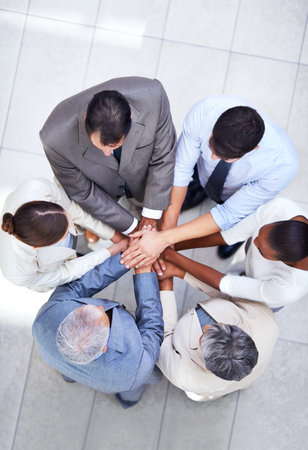 Lets do this team. a group of coworkers with their hands in a huddle.