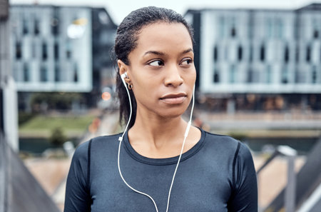 Music, fitness and face of black woman in city for wellness, healthy body and cardio workout in urban town. Sports, thinking and girl listening to audio for exercise, running and marathon trainingの写真素材