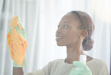Cleaning, window and black woman with spray and cloth for dust, bacteria and housekeeping service. Disinfection, hygiene and cleaner with girl and glass surface at home for washing, germs or sanitizeの写真素材
