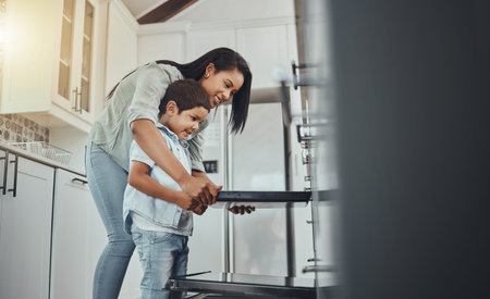 Baking, fun and child helping mother with food, cooking and learning by the oven in the kitchen. Breakfast, happy and mom and boy kid making lunch, dinner or a snack together in their family homeの写真素材