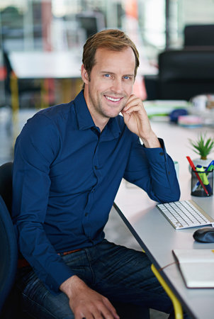 Total job fulfillment. Portrait of a handsome designer sitting at his workstation in an office.