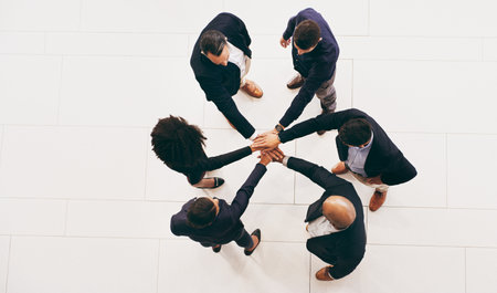Teamwork turns the wheels of a business. High angle shot of a group of businesspeople joining their hands in solidarity.の写真素材