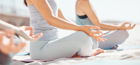 Women meditation in lotus with zen yoga class at the beach. Group of wellness female together on mat, leg crossed, finding inner mental balance and peace. Practice calming breathing exerciseの写真素材