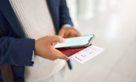 Hands, phone and passport chatting, typing or texting on mobile app or checking flight times at the airport. Hand of business employee holding smartphone and ID documents for travel, trip or journeyの写真素材