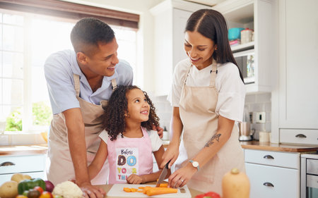 Happy family, love and cooking healthy food in the kitchen in preparation for a vegan diet for dinner or lunch together. Development, father and mother teaching child a vegetable salad recipe at homeの写真素材