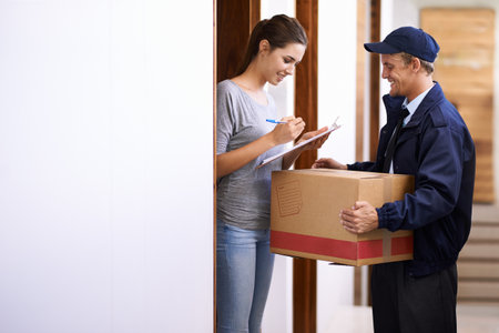 Delivering on his promise of fast and friendly service. a courier making a delivery to a smiling customer.の写真素材