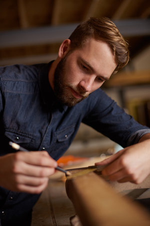 Trying his hand at woodwork. a young male carpenter working on a project in his workshop.の写真素材