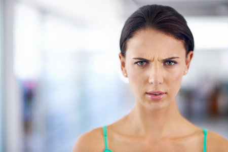 Turn that frown upside-down. Close up shot of a pretty brunette frowning at the camera.の写真素材