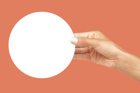 Hands, billboard and circle shape mockup for advertising, branding or marketing against studio background. Hand holding round poster, placard or empty banner for message, text or brand on copy spaceの写真素材