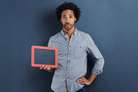 Giving you a sign. Portrait of a handsome young man with his hand on his hip holding a small chalk...