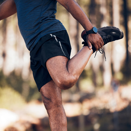 Black man, stretching legs and exercise outdoor in nature forest for fitness and healthy lifestyle. Sports person doing workout, training and muscle warm up for cardio body health and wellnessの写真素材