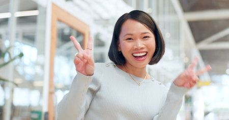 Peace sign, happy asian woman and face of success, motivation or pride in trendy office building in China. Portrait, excited female and v sign, hand emoji and celebration for happiness, winner or joyの写真素材