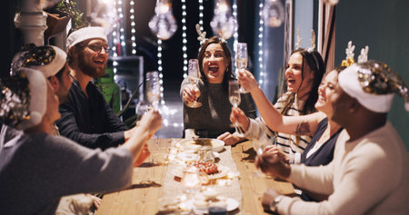 Christmas, party and friends toast with champagne at dinner, lunch and festival celebration together. Social event, cheers and men and women with alcohol enjoy, holiday, vacation and dinner partyの写真素材
