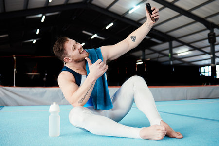 Man, gymnast and thumbs up for fitness selfie, profile picture or vlog in social media sitting on floor at the gym. Happy male acrobat smile for photo, memory or post showing thumb emoji, like or yesの写真素材