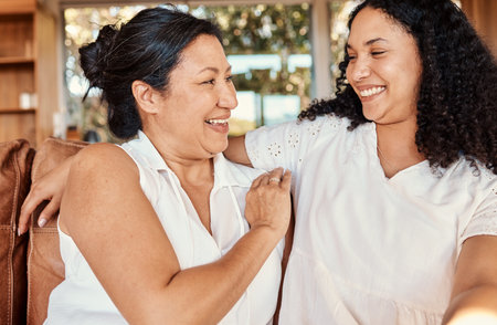Woman, senior mother and smile of family on a living room sofa with happiness and bonding. Mama love, support and happy elderly care with women on a lounge couch in a house together with a hugの写真素材
