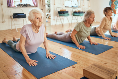 Yoga, stretching and senior women at a wellness, rehabilitation and retirement spa community for exercise, fitness and health. Workout, pilates and healthy elderly people, friends or group on floorの写真素材