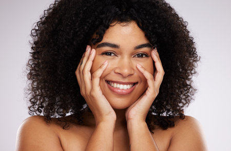 Portrait, beauty and afro with a black woman in studio on a gray background for natural hair treatment. Face, skincare and haircare with an attractive young female model posing to promote cosmeticsの写真素材