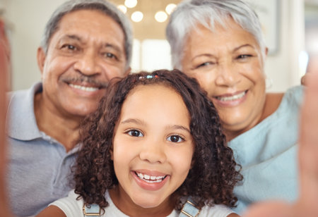 Happy grandparents, girl child taking a selfie with senior couple and visit them in retirement. Kid loves hnaging out with elders, sharing online with social media and enjoy time together as a familyの写真素材