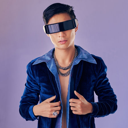 Asian, man and vr with future glasses in studio for aesthetic, jewelry or cyberpunk by lavender wall. Futuristic fashion model, metaverse and metal jewellery in sci fi sunglasses for virtual realityの写真素材