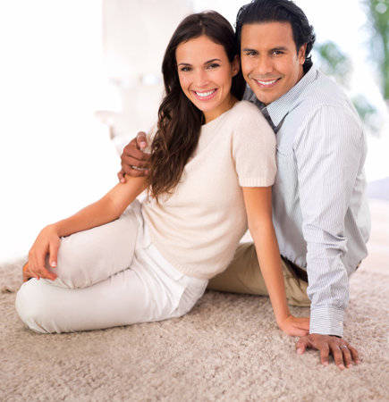 Relaxing with his beautiful wife. A husband and wife relaxing together on the living room carpet.の写真素材