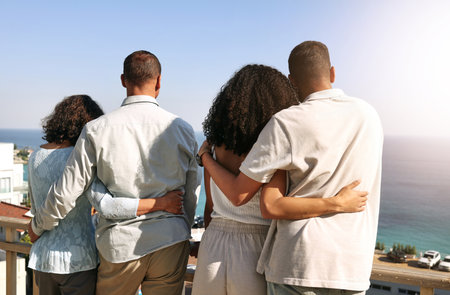 Hug, love and family with a view of ocean during a vacation, freedom and bonding in Bali. Affection, holiday and back of parents and couple on a balcony to look at the beach for a break and travelの写真素材
