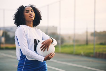 Sports, netball and portrait of female with a ball after match, exercise or training on the court. Confidence, fitness and serious black woman athlete standing on field for game, workout or practice.の写真素材