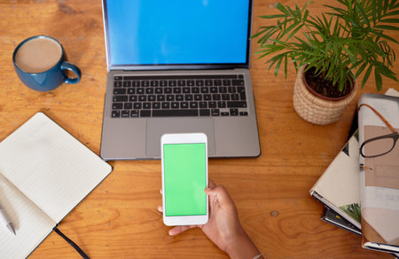 Green screen, laptop and phone in hands for mobile app, multimedia mockup and product placement space. Student planning with smartphone mock up for social media marketing, communication or ux designの写真素材