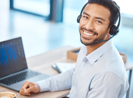 Asian call center man with headset and laptop working for contact us support, telemarketing sales and consulting company. Corporate customer service help and business success agent employee in officeの写真素材