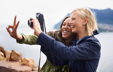 Snapshots of peace. A shot of two young women taking a self portrait on a road trip.の写真素材
