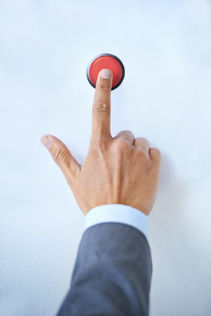 Sounding the alarm. a businessman with his finger on a red button.の写真素材