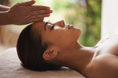 Massaging the body and mind. a beautiful young woman getting a head massage at a spa.の写真素材