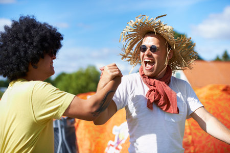 Boy buffoonery. two male friends having fun at an outdoor festival.の写真素材