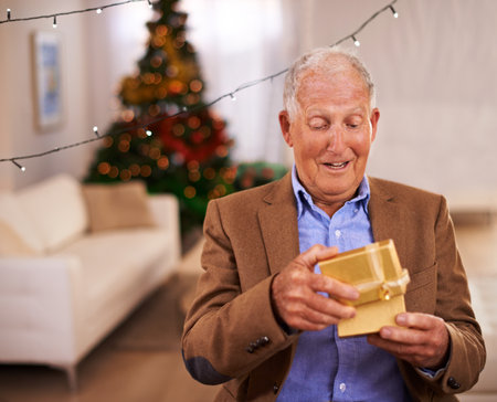 What a surprise. an elderly man opening a christmas present.の写真素材