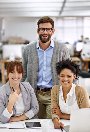 Positive young professionals. a group of young office professionals talking over a digital tablet.の写真素材
