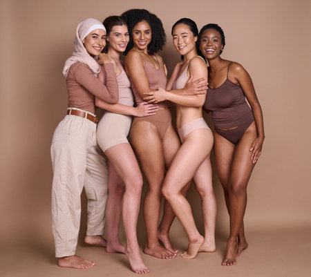 Beauty skincare, diversity and group of women in studio on a brown background. Underwear, makeup cosmetics and portrait of different female models posing for self love, empowerment or body positivityの写真素材