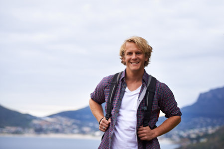 He loves to hike. Portrait of a handsome young male hiker standing outside.の写真素材