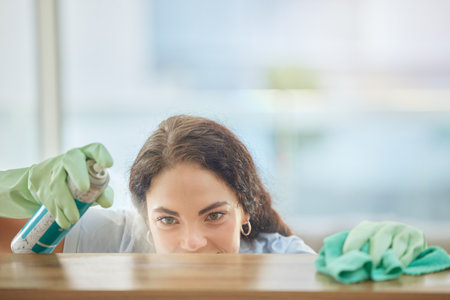 Spray, table or woman cleaning furniture surfaces with product for messy or dirty bacteria in house living room. Cleaning service, job or cleaner with liquid detergent bottle wipes wet or dusty woodの写真素材