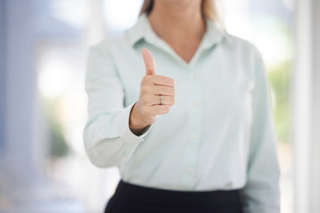 Business woman, hand and thumbs up for yes, good job or corporate success at the workplace. Female showing great thumbsup gesture or sign in congratulations, approval or good news at the officeの写真素材